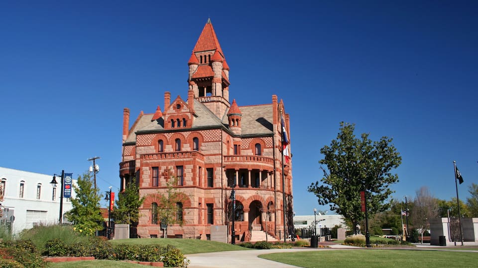 A large, historic red brick building with a tower and arched windows.
