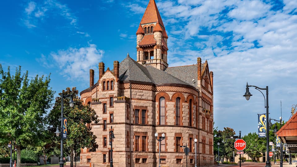 A historic building with a tower, arched windows, and a red roof.