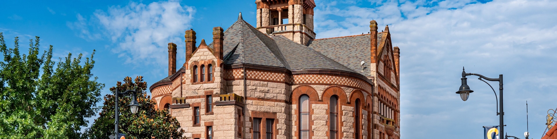 A historic building with a tower, arched windows, and a red roof.