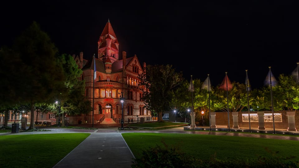 A large, historic building with a prominent tower at night.