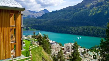 Edificio de madera con vistas a un lago turquesa con veleros, rodeado de montañas boscosas.