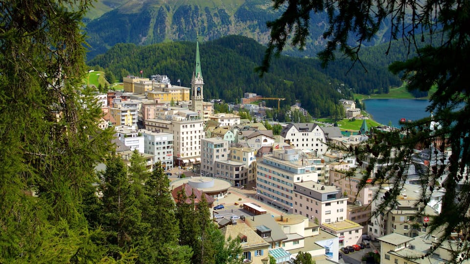 A town with a prominent church tower, surrounded by buildings and mountains.
