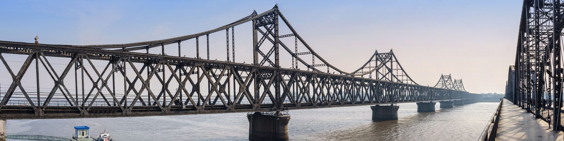 Un puente colgante grande sobre un río, con una embarcación en primer plano.
