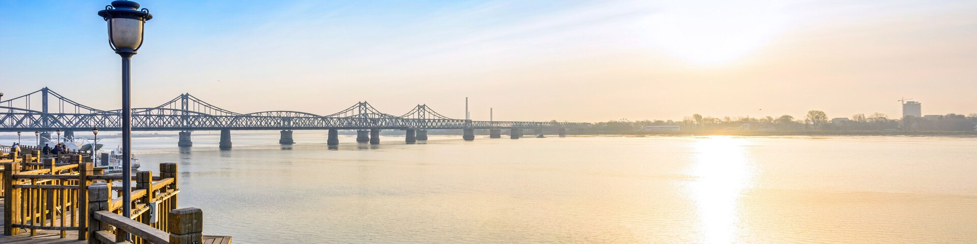 Un puente sobre un río tranquilo con un muelle de madera a la izquierda.