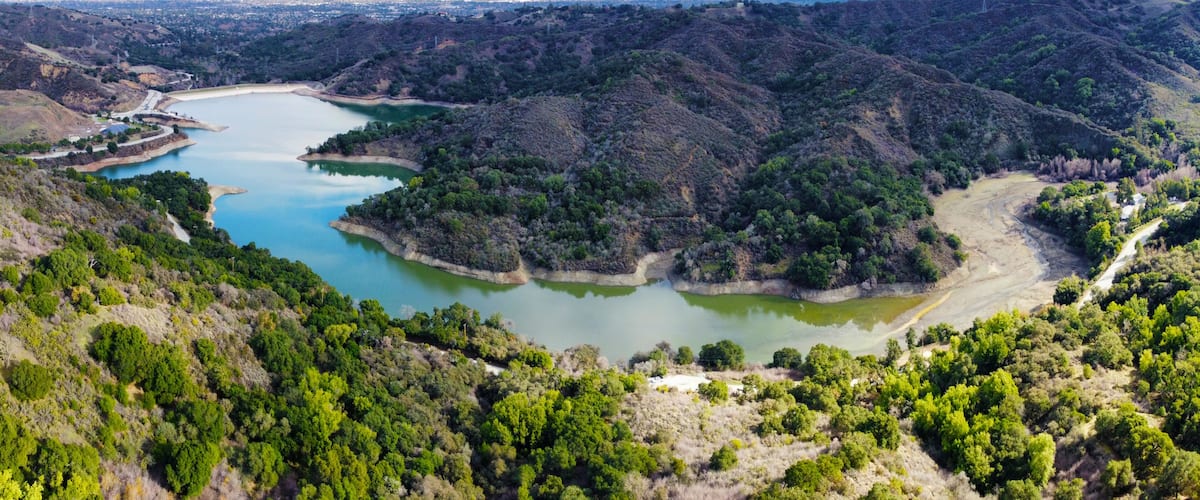 Aerial panoramic view of Stevens Creek Reservoir in Santa Clara County, California during winter. Background Silicon Valley.