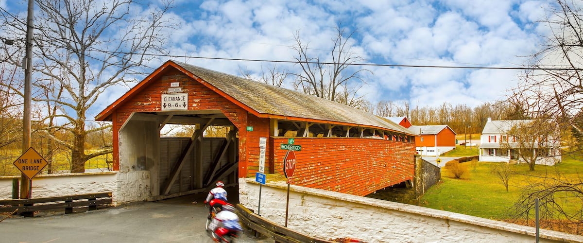 A covered bridge with a 'Clearance' sign, a 'One Lane Bridge' sign, and a 'Stop' sign.