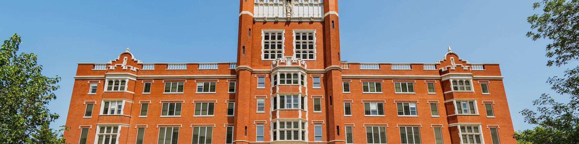 A large red brick building with a central tower, large windows, and a staircase leading to the entrance.