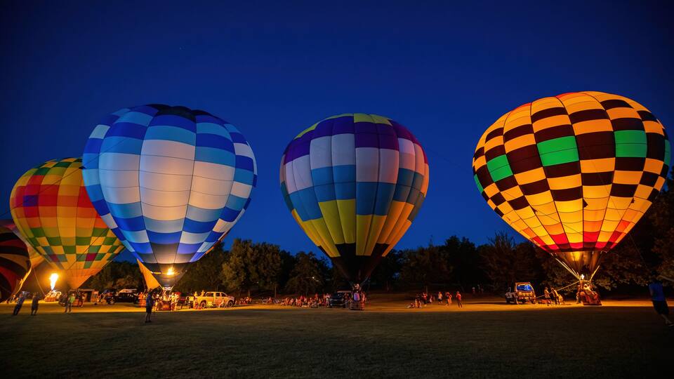 Three hot air balloons with colorful patterns against a twilight sky.
