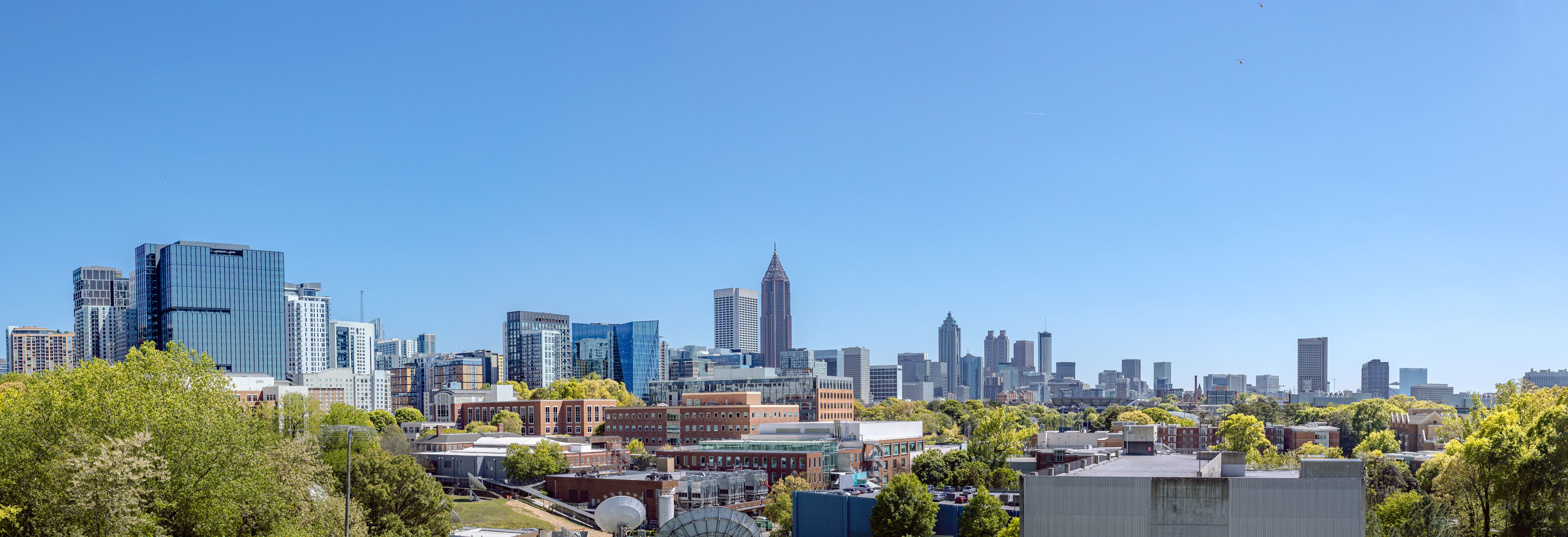 Downtown, Midtown Atlanta Skyline showing several prominent buildings, highways, cars and hotels under a blue sky.