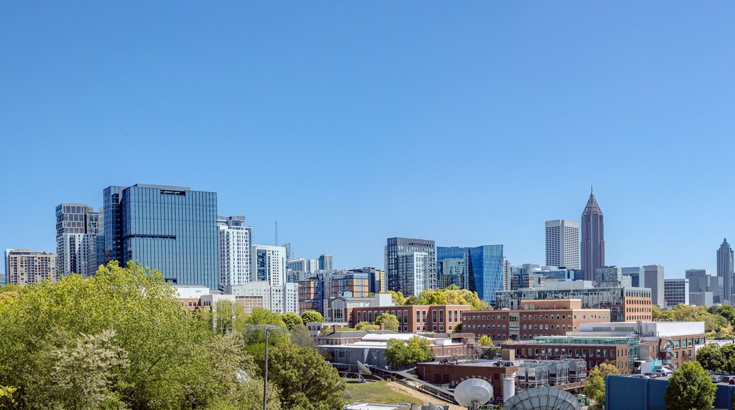 Downtown, Midtown Atlanta Skyline showing several prominent buildings, highways, cars and hotels under a blue sky.