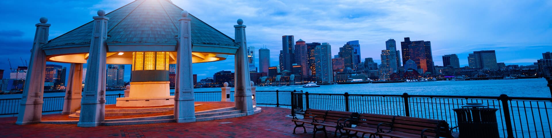 A waterfront gazebo with a city skyline in the background.