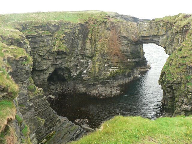 Vat of Kirbuster. The vat is a "gloup" - a partially collapsed sea cave with part of the roof remaining and forming an arch. (The name is sometimes spelt Kirbister. The SNH sign at the nearby car park has both spellings.)