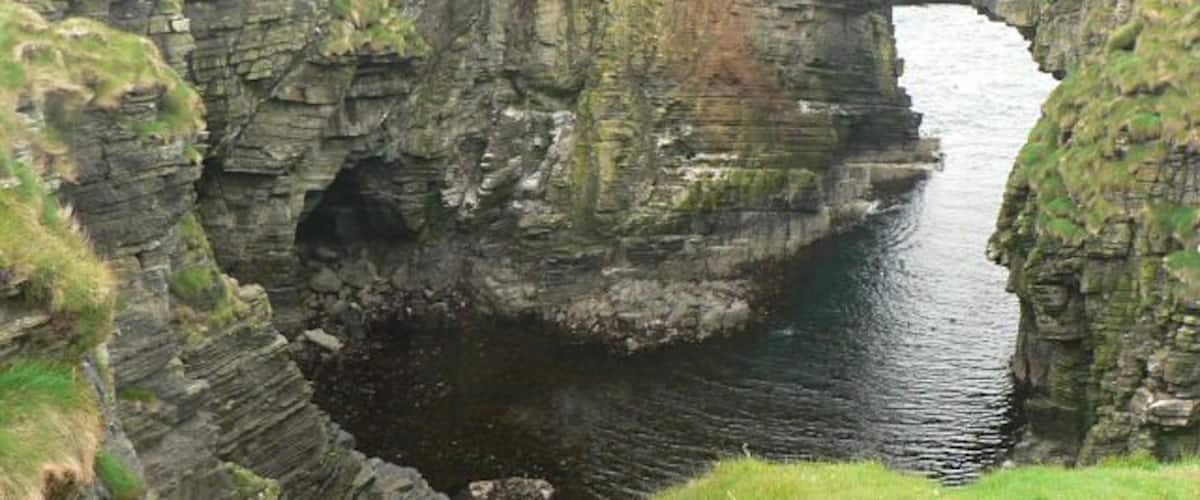 Vat of Kirbuster. The vat is a "gloup" - a partially collapsed sea cave with part of the roof remaining and forming an arch. (The name is sometimes spelt Kirbister. The SNH sign at the nearby car park has both spellings.)