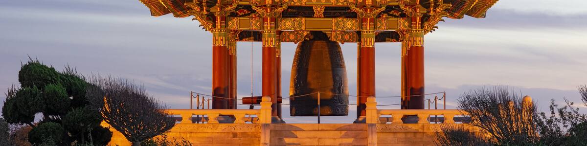 Un pavillon traditionnel, doté d’un toit incurvé et de décorations raffinées, se dressant sur fond de ciel crépusculaire.