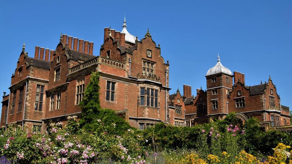 A large, historic brick building with multiple towers and a dome.