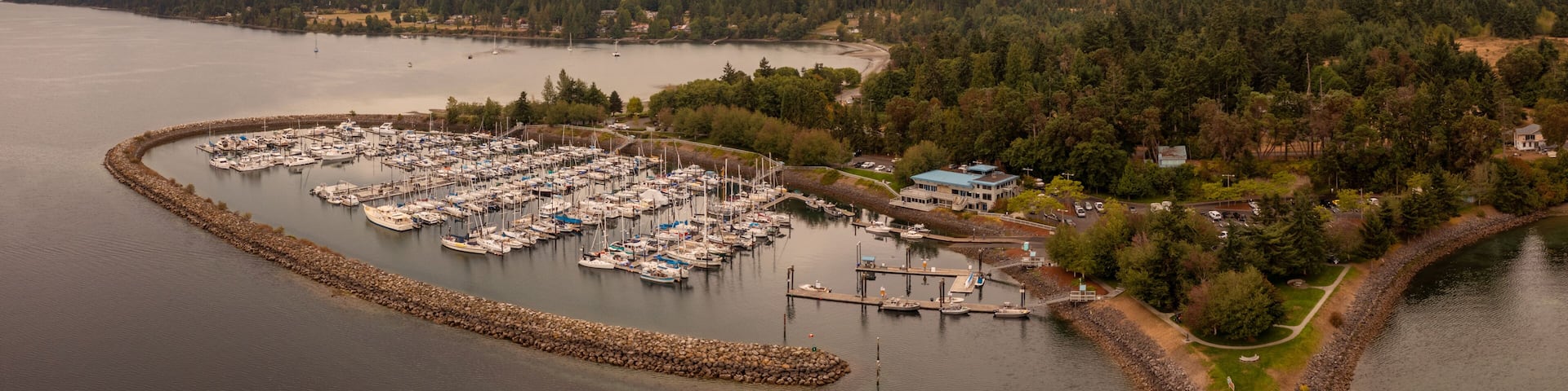 A marina surrounded by forested hills and a calm lake.