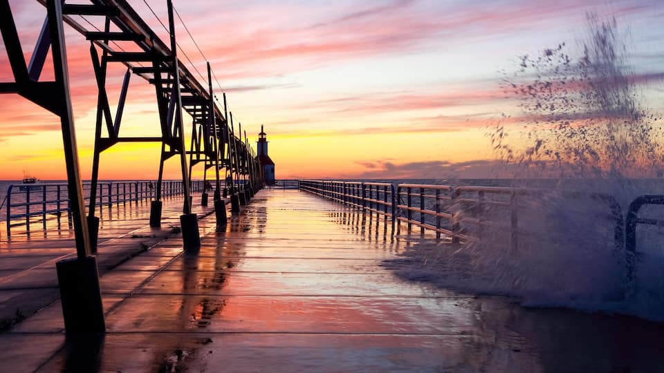 A pier extending into the water with a sunset in the background.