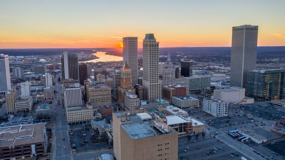 A cityscape with a river, high-rise buildings, and a sunset.