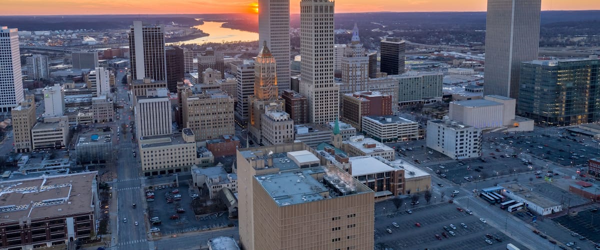 A cityscape with a river, high-rise buildings, and a sunset.