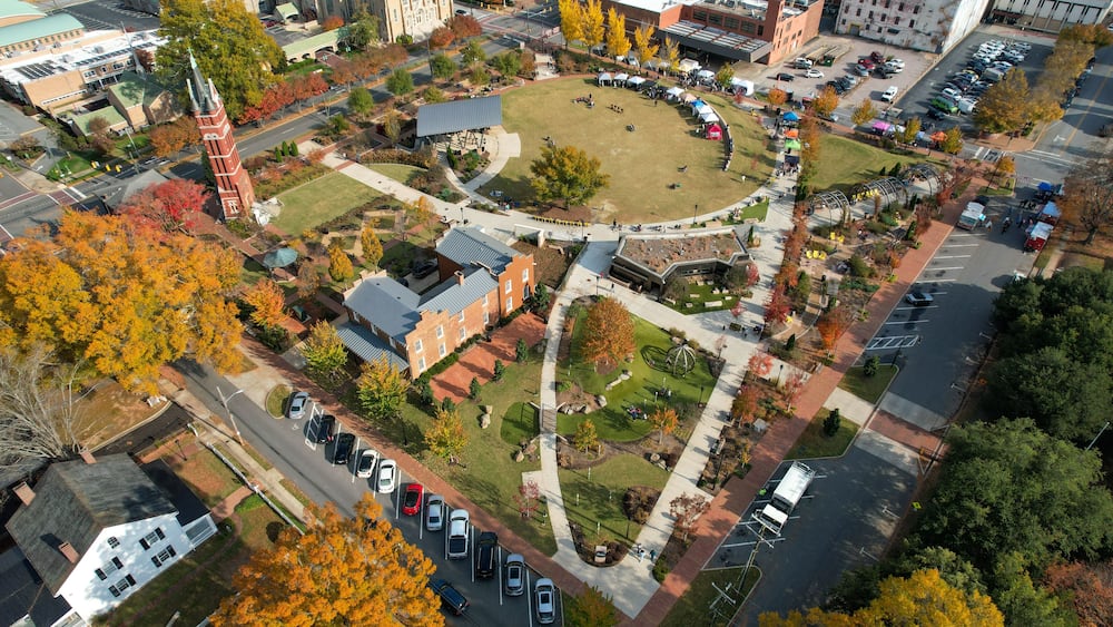An aerial view of a university campus with a central lawn, surrounding buildings, and a parking lot.