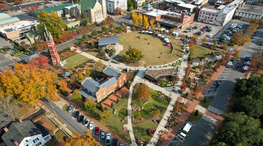 An aerial view of a university campus with a central lawn, surrounding buildings, and a parking lot.