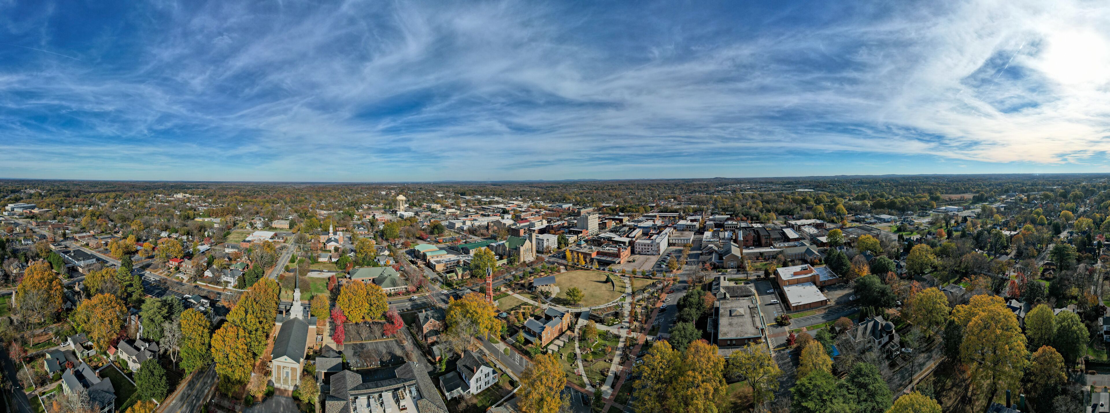 An aerial view of a town with autumn-colored trees, a prominent church, and a large water tower.