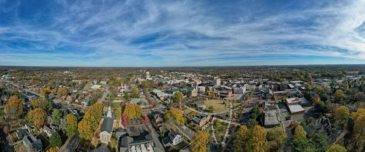 An aerial view of a town with autumn-colored trees, a prominent church, and a large water tower.