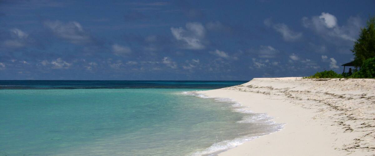 A beach with clear turquoise water and a sandy shore.