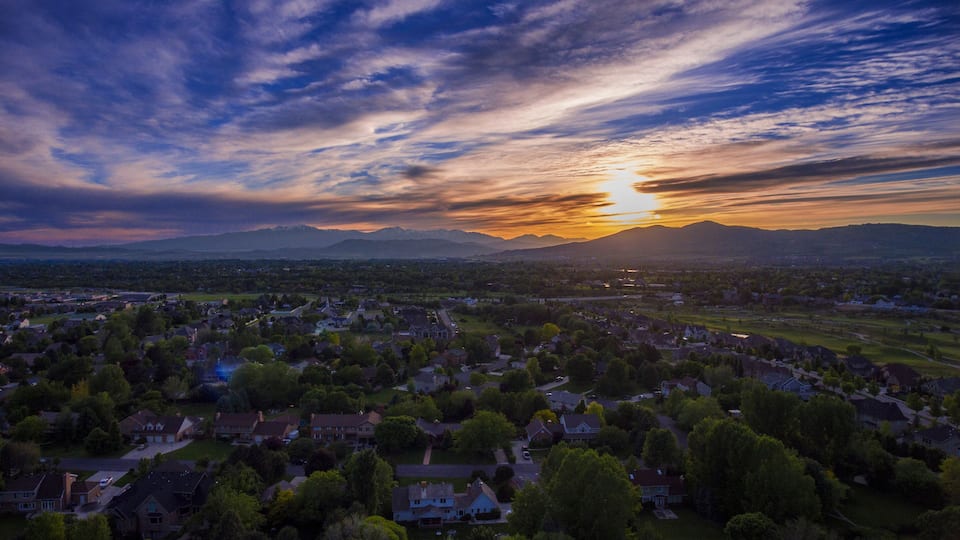 A sunset over a residential area with mountains in the background.