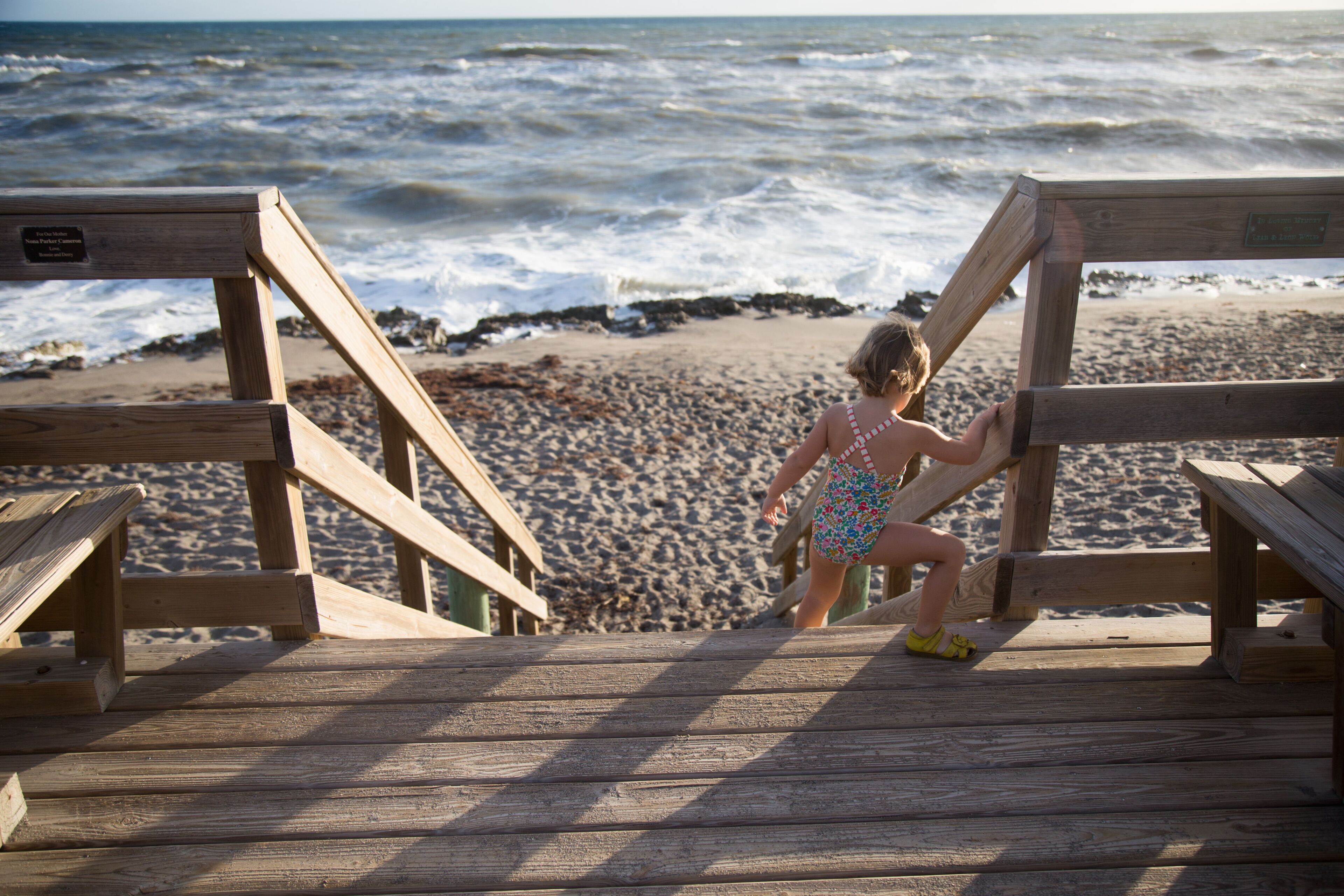 A child climbs down a beach stairway. 