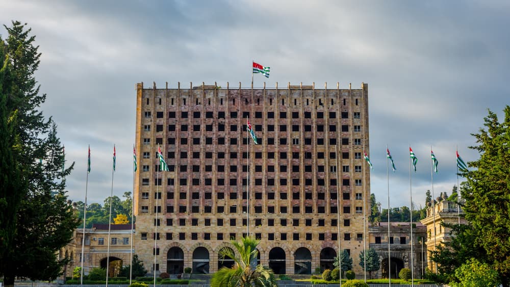A large, multi-story building with a grid of windows and a flag on top.
