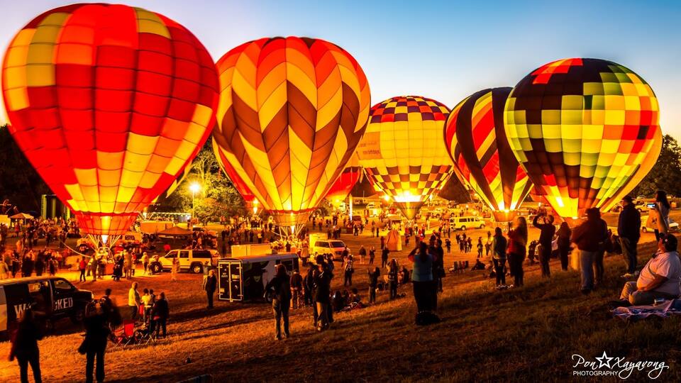 A hot air balloon festival with large, colorful balloons and a crowd of people.