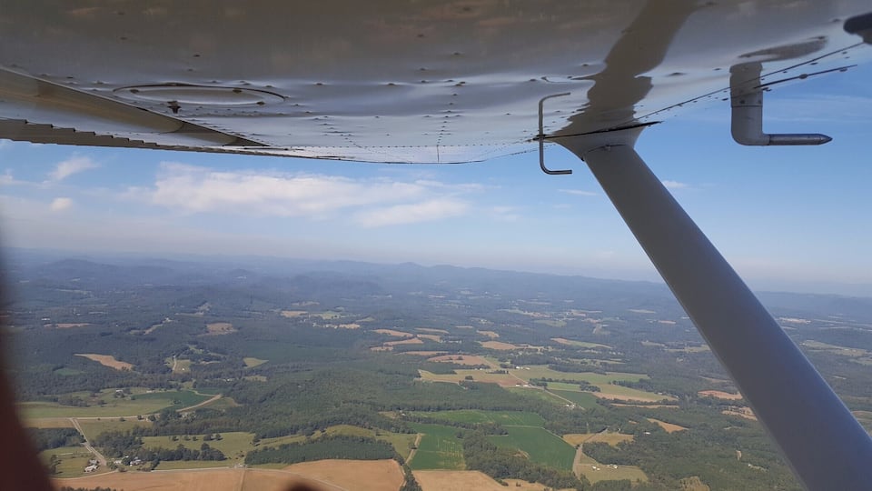 An aerial view of a landscape with fields, forests, and distant mountains.