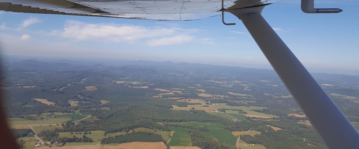 An aerial view of a landscape with fields, forests, and distant mountains.