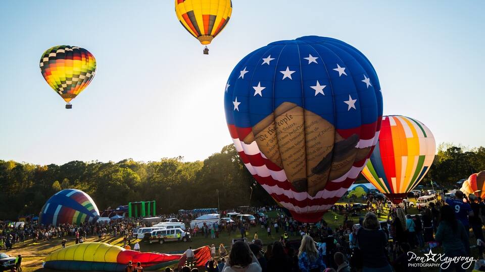 A hot air balloon festival with colorful balloons, including one with a star pattern and another with a rainbow design.