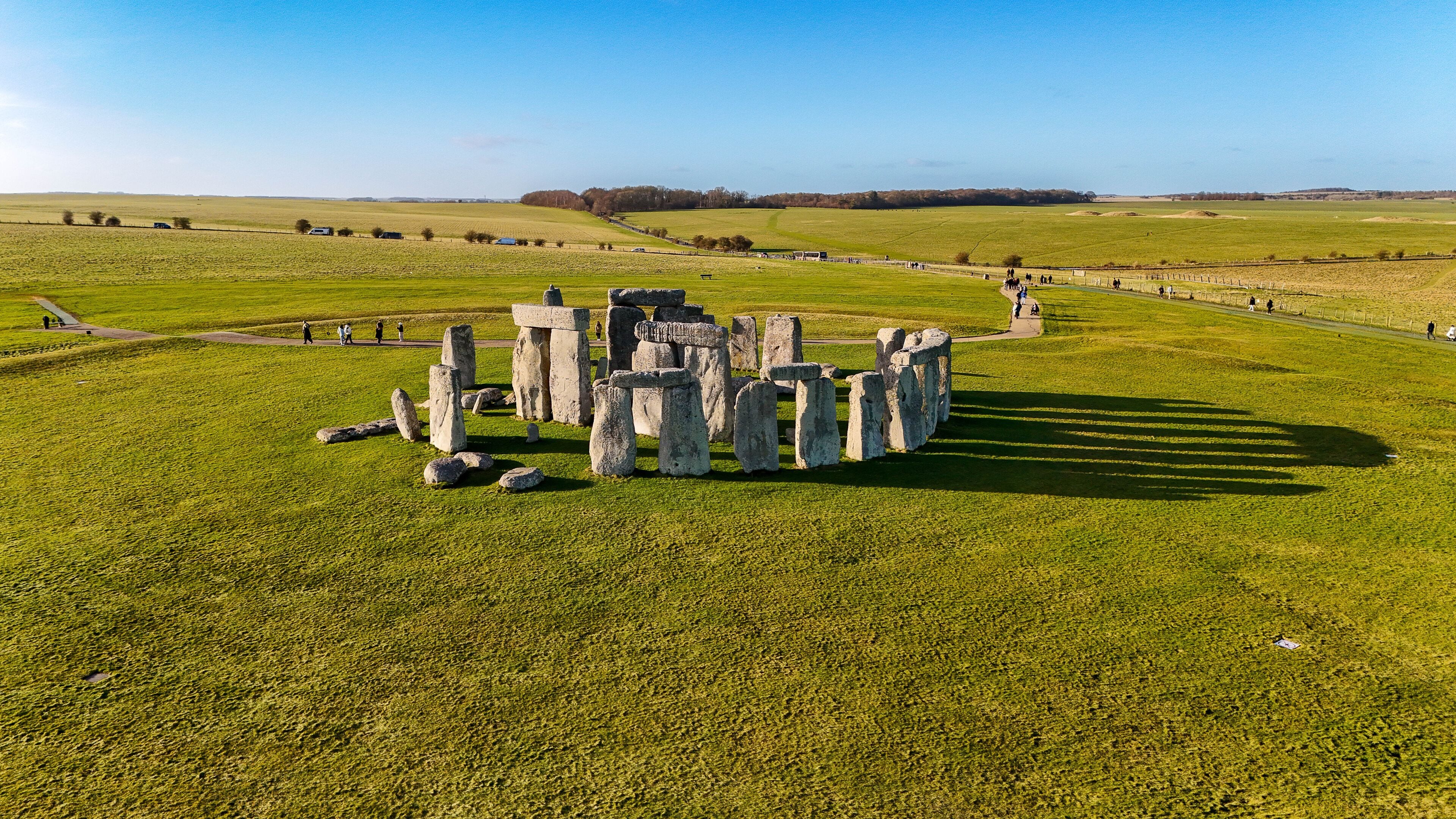 Stonehenge in a grassy field with a clear sky.