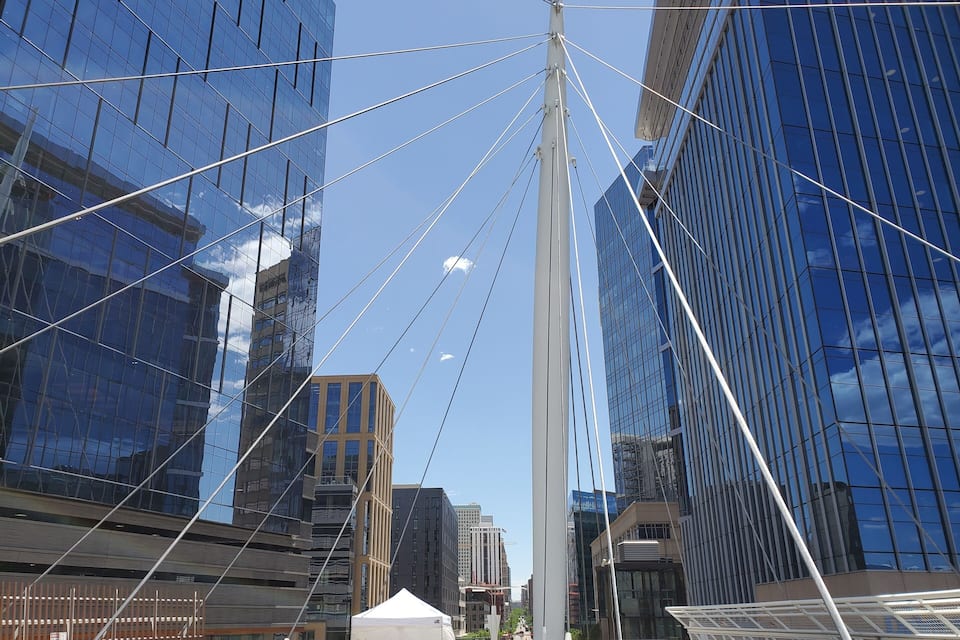 Paisagem urbana moderna com edifícios altos de vidro e uma imponente torre branca.