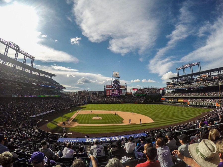 A baseball stadium with a large crowd, a baseball diamond, and a scoreboard.