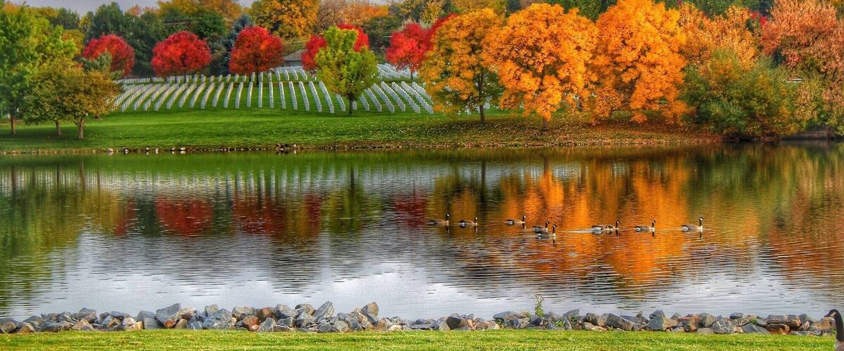 A lake with ducks, surrounded by trees in autumn colors.