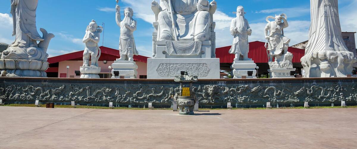 A collection of white statues in an open plaza with a clear blue sky.