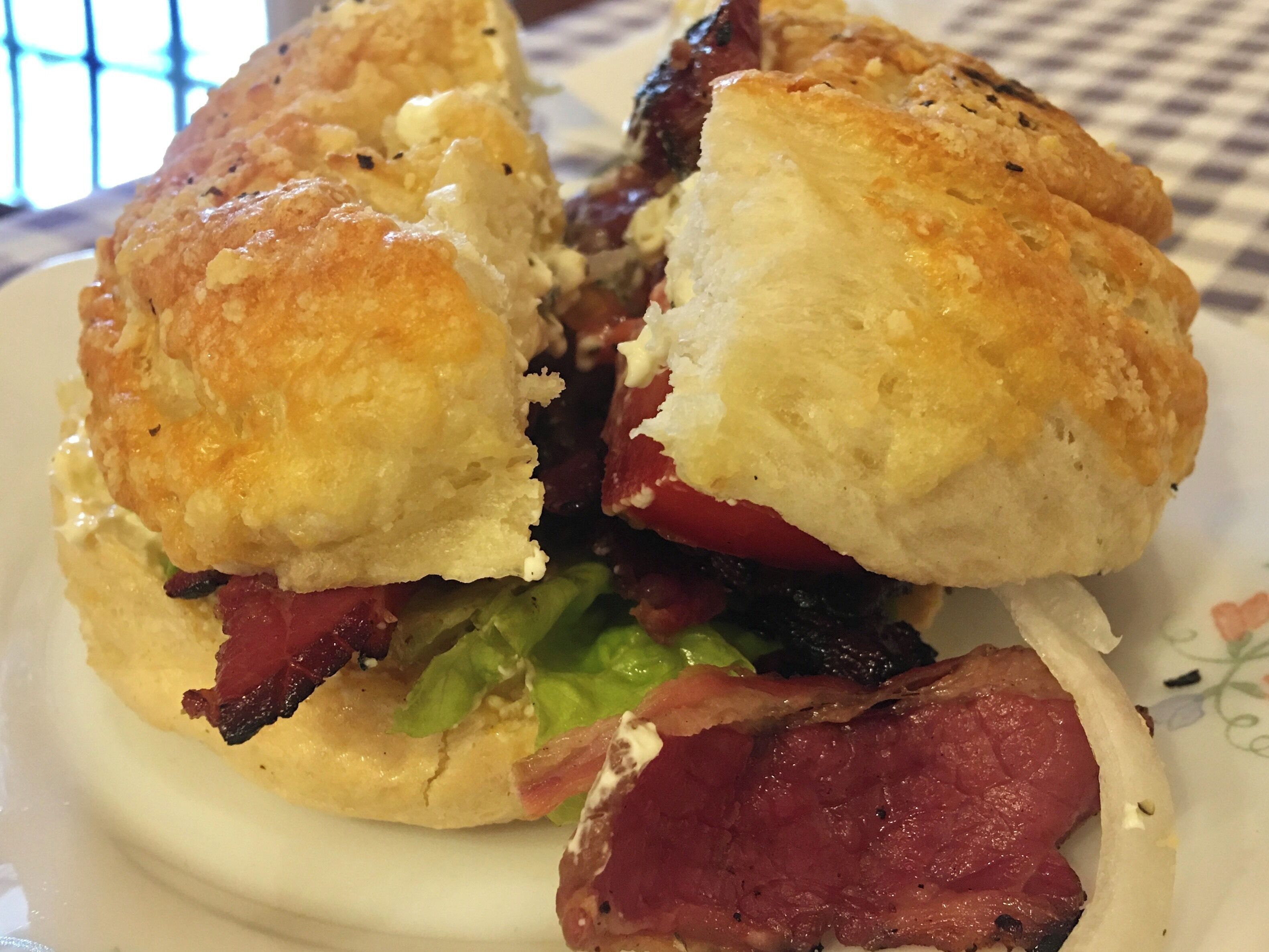 A sandwich with a toasted bun, lettuce, tomato, and bacon.