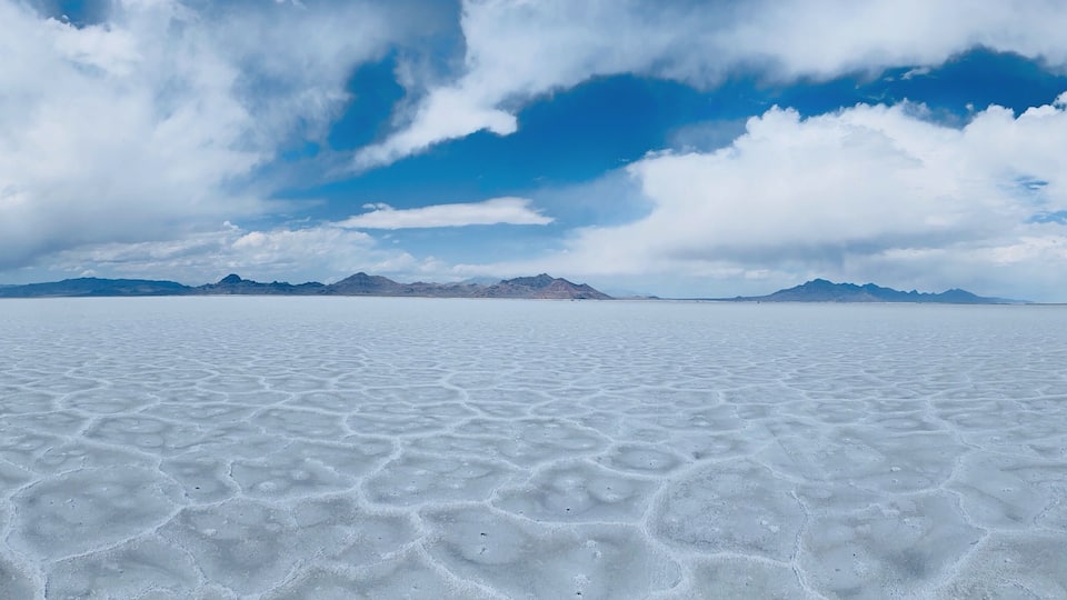 A vast salt flat with a clear sky and distant mountains.
