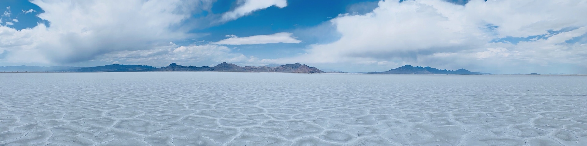 Uma vasta planície salina com céu limpo e montanhas ao longe.