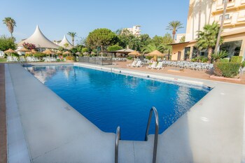 Una piscina al aire libre, sombrillas, tumbonas