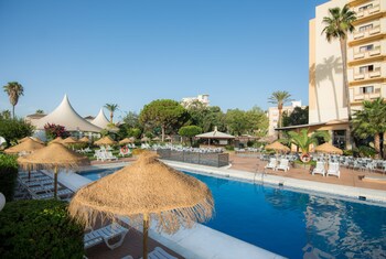 Una piscina al aire libre, sombrillas, tumbonas
