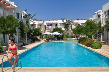 Una piscina al aire libre, sombrillas, tumbonas