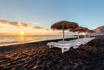 Sulla spiaggia, sabbia scura, lettini da mare, ombrelloni