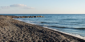 Sulla spiaggia, sabbia scura, lettini da mare, ombrelloni